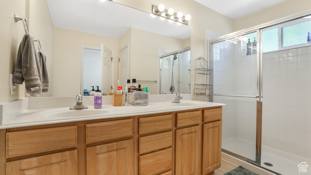 Full bath featuring a shower stall, double vanity, and tile patterned floors