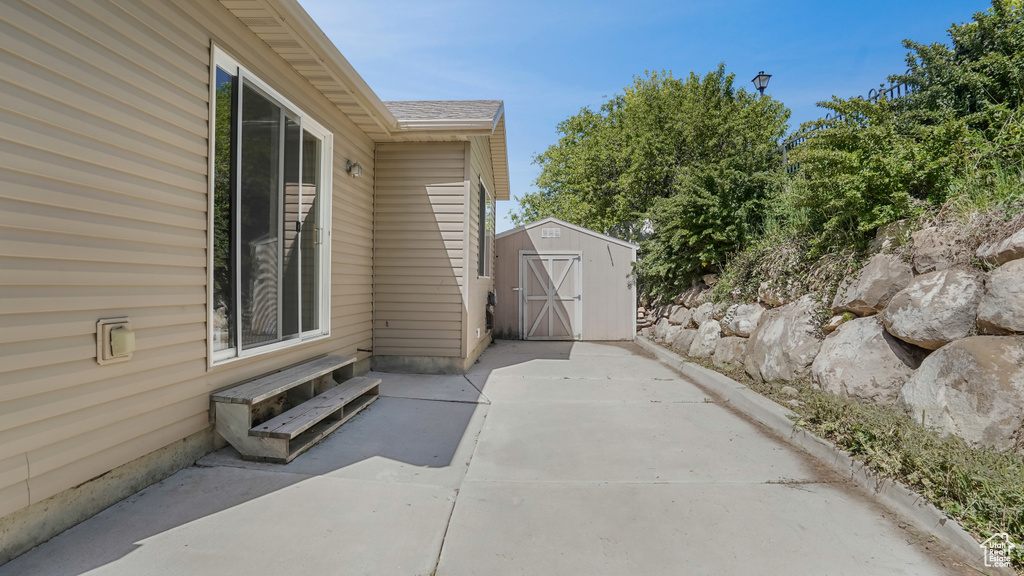 View of side of property featuring a storage shed, a patio area, an outbuilding, and entry steps