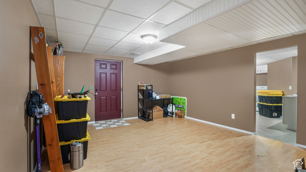 Below grade area featuring wood finished floors, a drop ceiling, and baseboards