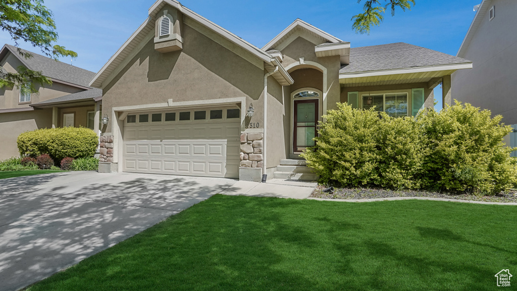 View of front facade with an attached garage, stucco siding, a front lawn, and concrete driveway
