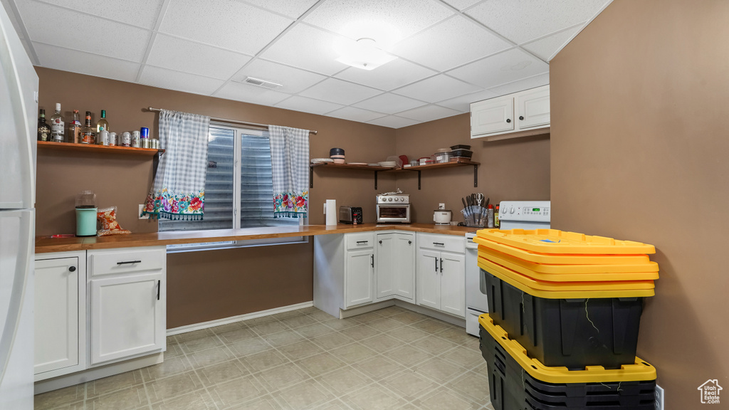 Kitchen with open shelves, white appliances, butcher block countertops, a paneled ceiling, and white cabinetry