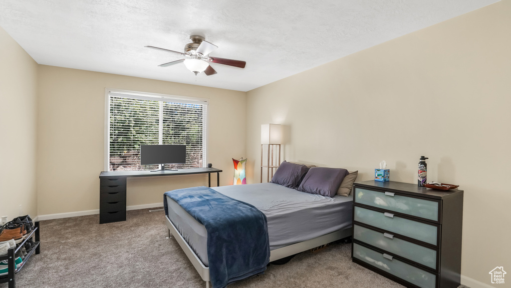 Carpeted bedroom featuring ceiling fan and baseboards