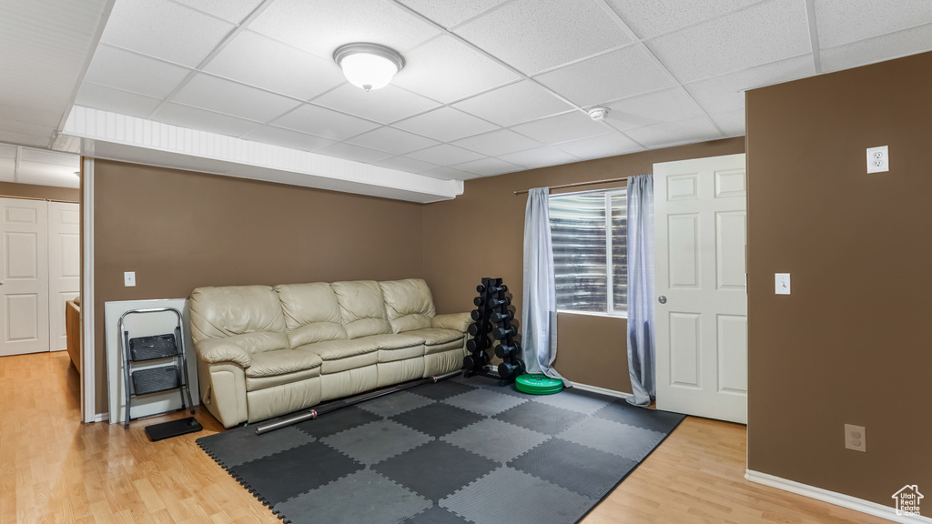 Living area featuring wood finished floors, a paneled ceiling, and baseboards