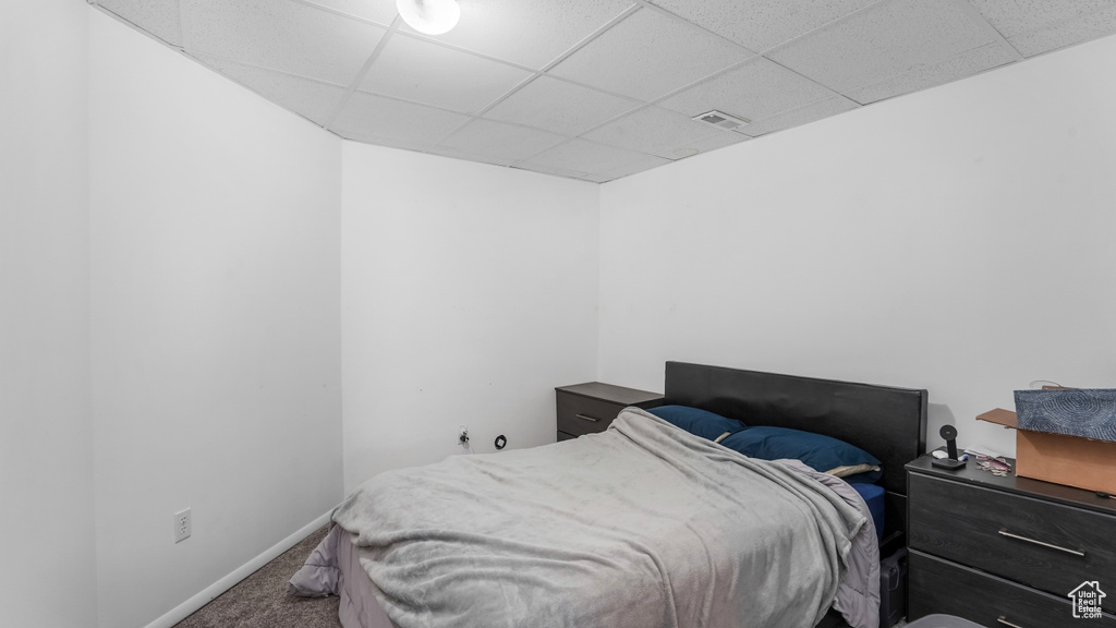 Carpeted bedroom featuring a drop ceiling and baseboards