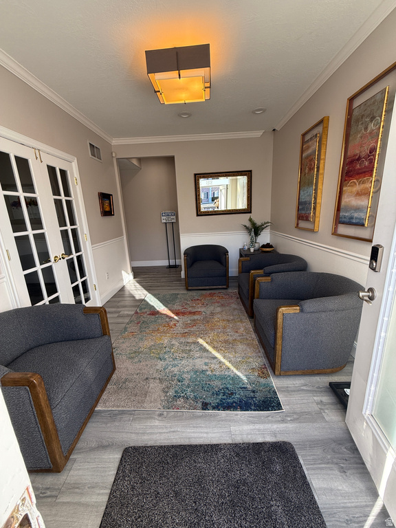 Living room with ornamental molding, wood finished floors, and french doors