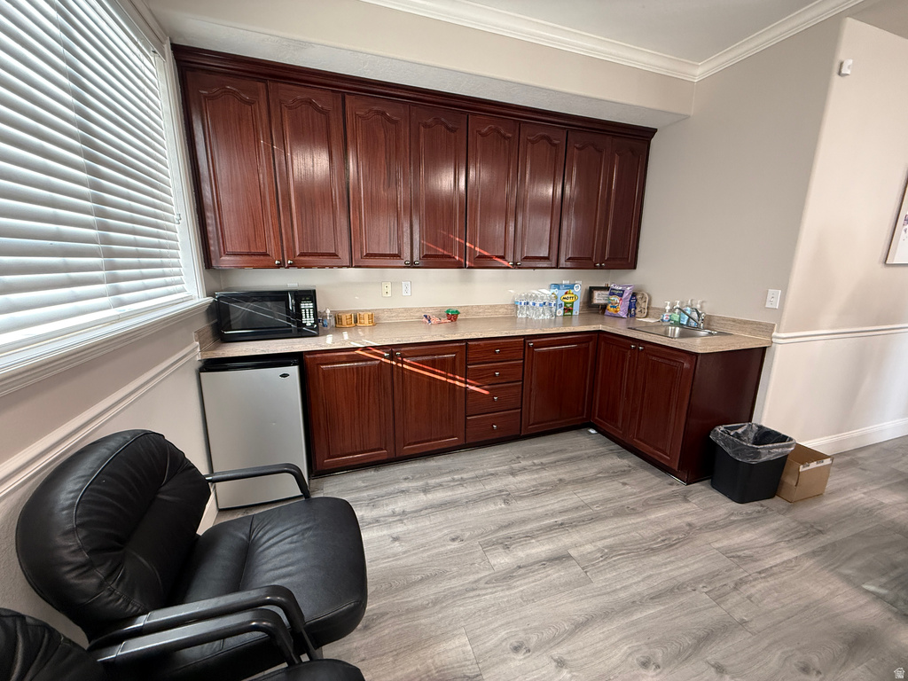 Kitchen featuring crown molding, stainless steel fridge, light wood finished floors, black microwave, and dark brown cabinetry