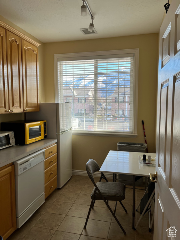 Dining space with plenty of natural light, light tile patterned flooring, an office area, and baseboards