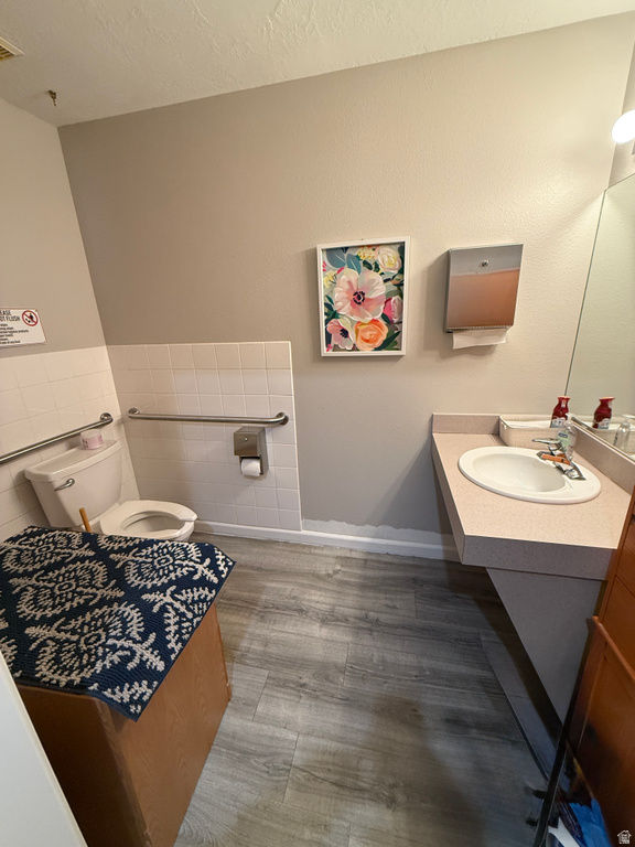 Bathroom featuring vanity, light wood-style floors, and tile walls