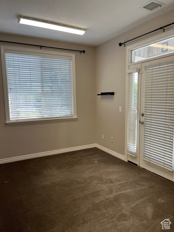 Empty room featuring dark carpet and baseboards