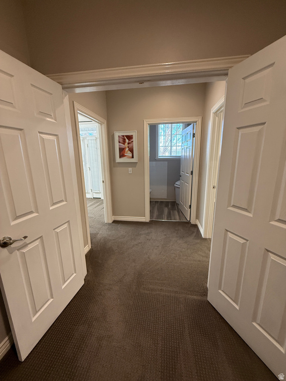 Hallway with baseboards and dark carpet