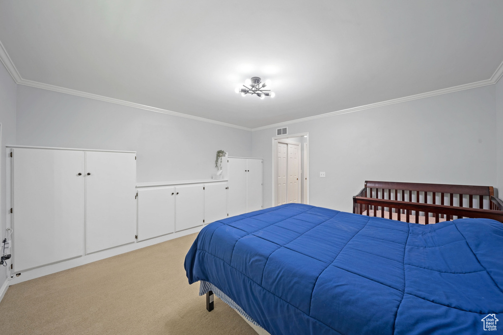 Bedroom with crown molding and light carpet
