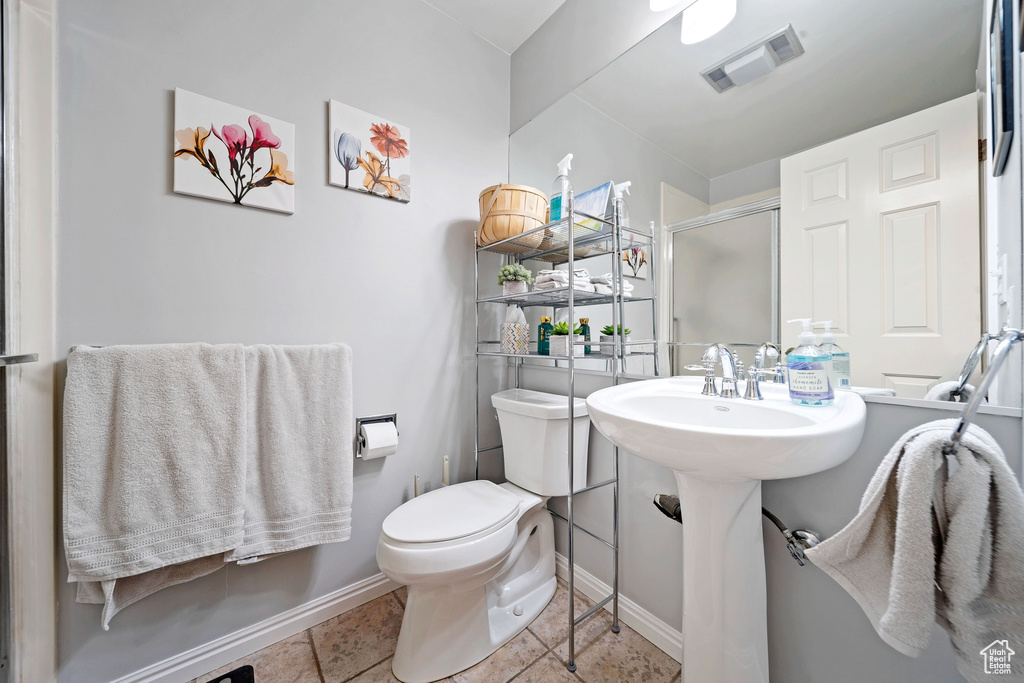 Full bath featuring toilet, a shower stall, tile patterned floors, and baseboards