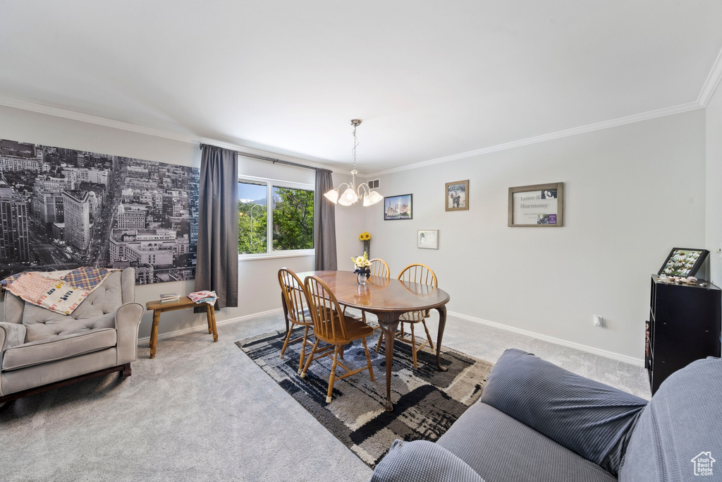 Carpeted dining area featuring crown molding, a chandelier, and baseboards