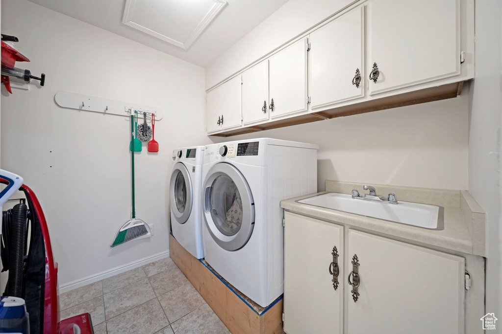 Washroom with separate washer and dryer, cabinet space, attic access, and baseboards