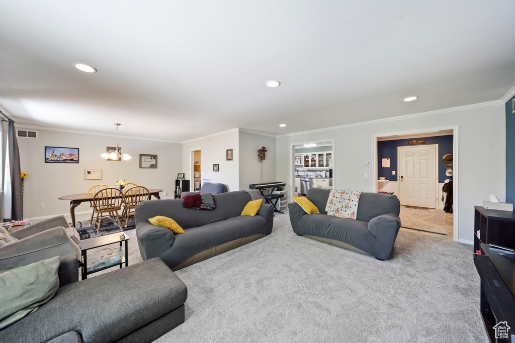 Carpeted living area featuring ornamental molding, a chandelier, recessed lighting, and baseboards