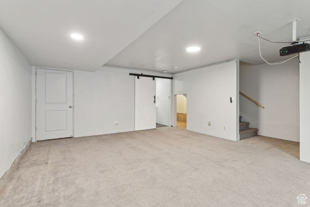 Finished basement with carpet floors, stairs, recessed lighting, and a barn door