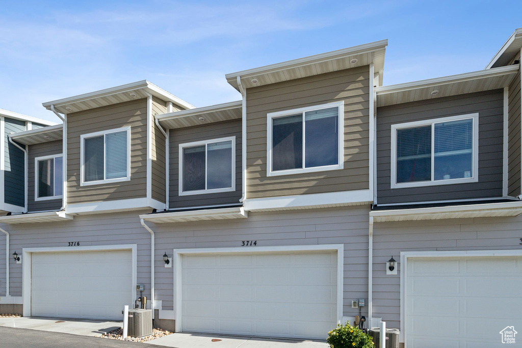 View of property featuring an attached garage and central AC