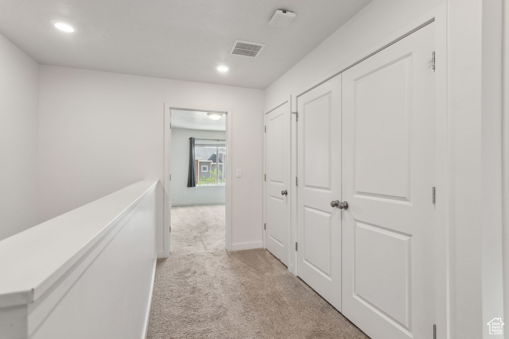 Hallway featuring light carpet, recessed lighting, and baseboards