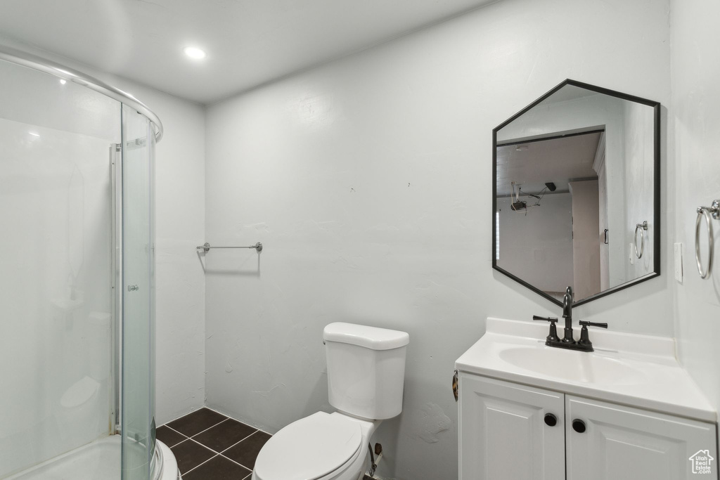 Bathroom featuring toilet, a stall shower, tile patterned floors, and vanity