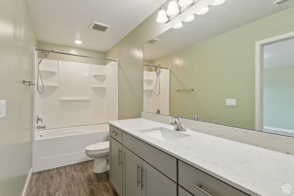 Bathroom with wood finished floors, toilet, vanity, and shower / tub combination