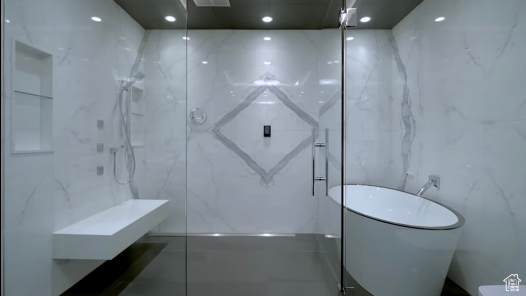 Full bath with a marble finish shower and a freestanding tub