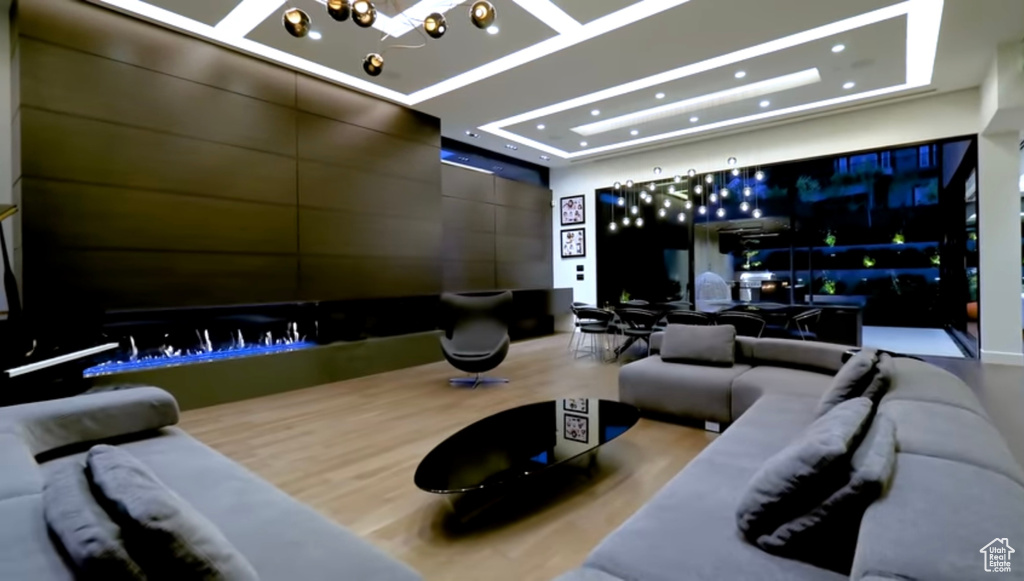 Home theater room featuring a raised ceiling, recessed lighting, and wood finished floors