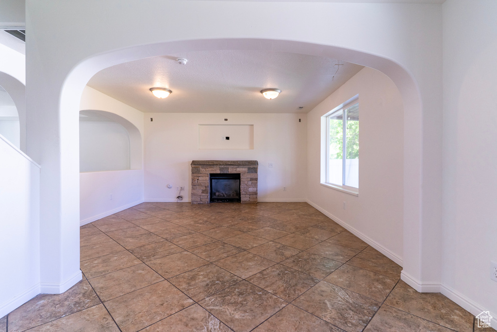 Unfurnished living room with a stone fireplace and baseboards
