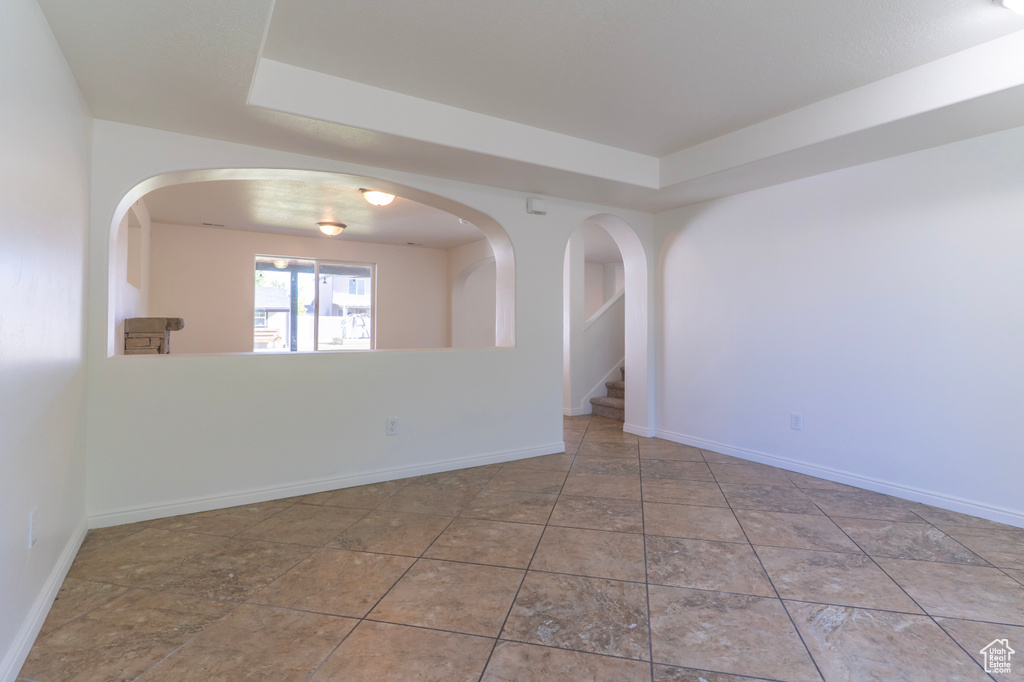 Unfurnished room with a tray ceiling and baseboards