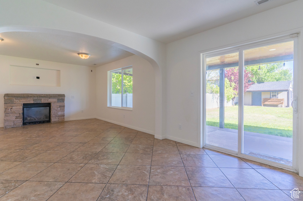 Unfurnished living room featuring baseboards, arched walkways, and tile patterned flooring