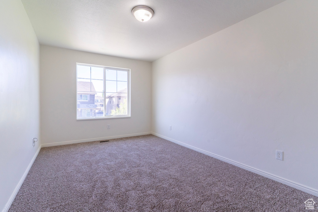 Carpeted empty room featuring baseboards
