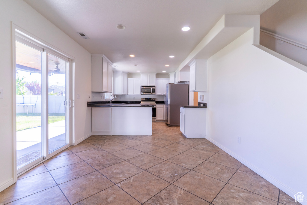 Kitchen with appliances with stainless steel finishes, dark countertops, a sink, white cabinetry, and recessed lighting