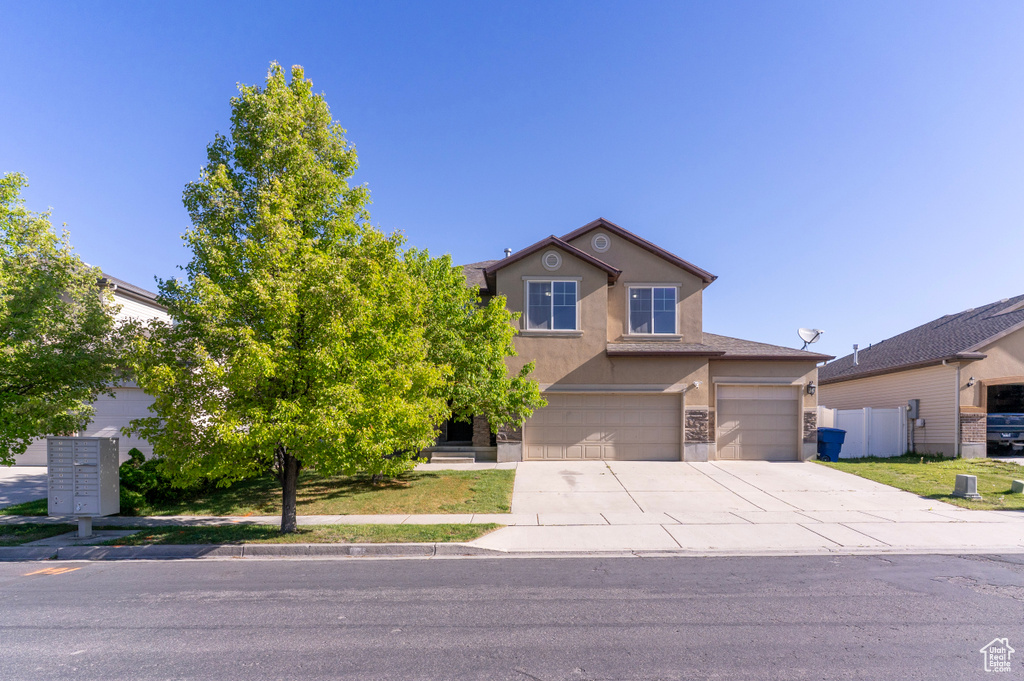Traditional-style house featuring stucco siding, driveway, a garage, and fence