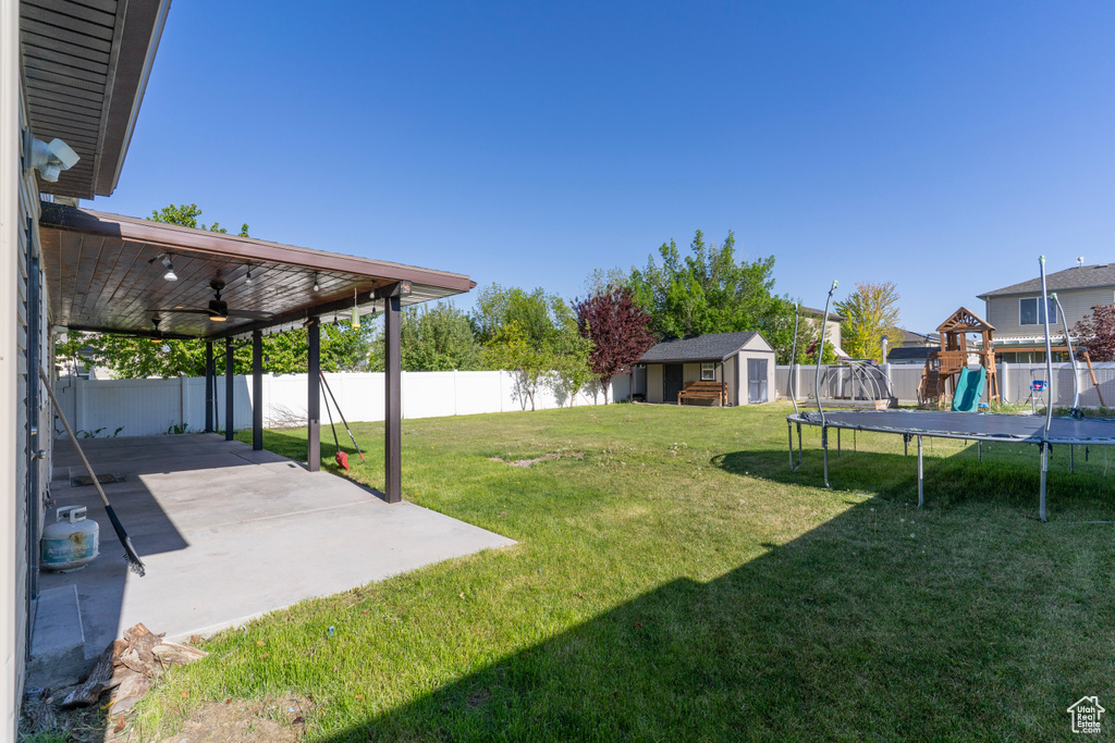 View of yard with a trampoline, a shed, a patio, an outdoor structure, and a ceiling fan