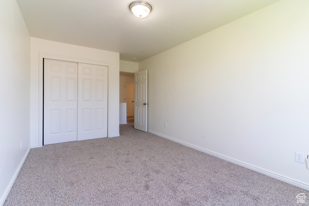 Unfurnished bedroom featuring carpet, a closet, and baseboards