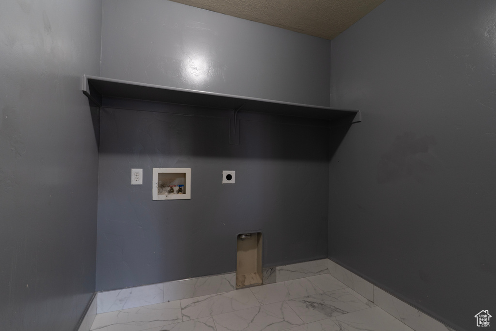 Washroom featuring hookup for an electric dryer, washer hookup, baseboards, light marble finish floors, and a textured ceiling