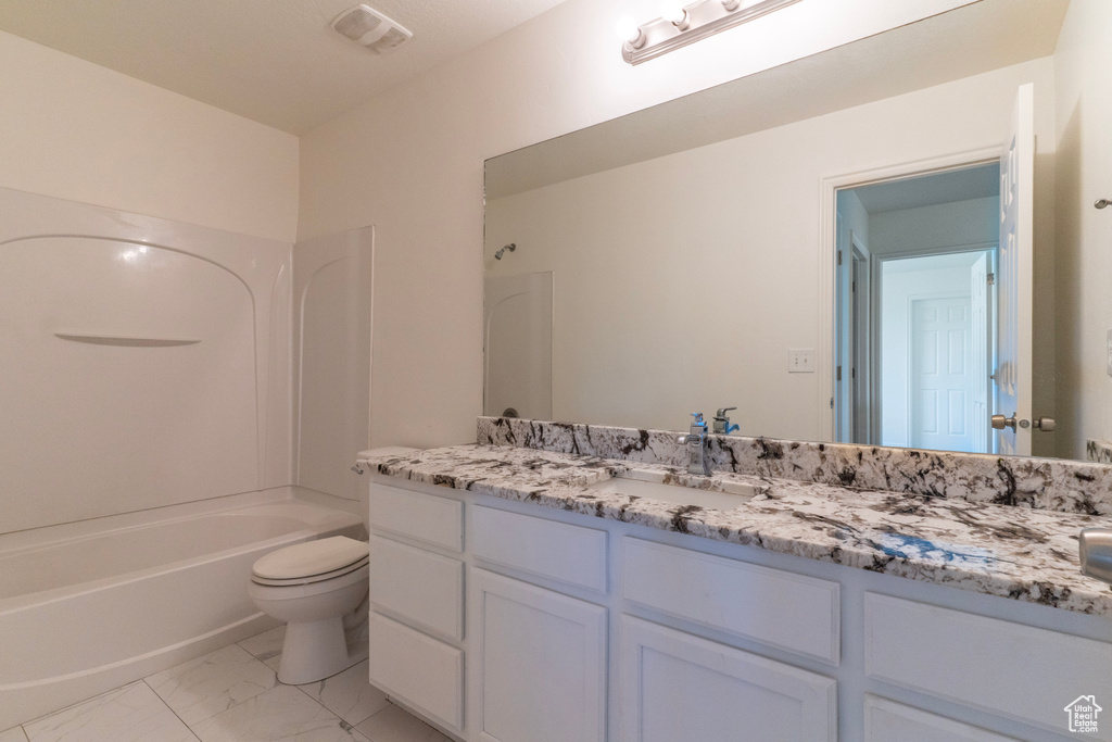 Full bath with marble look tiles, toilet, vanity, and washtub / shower combination