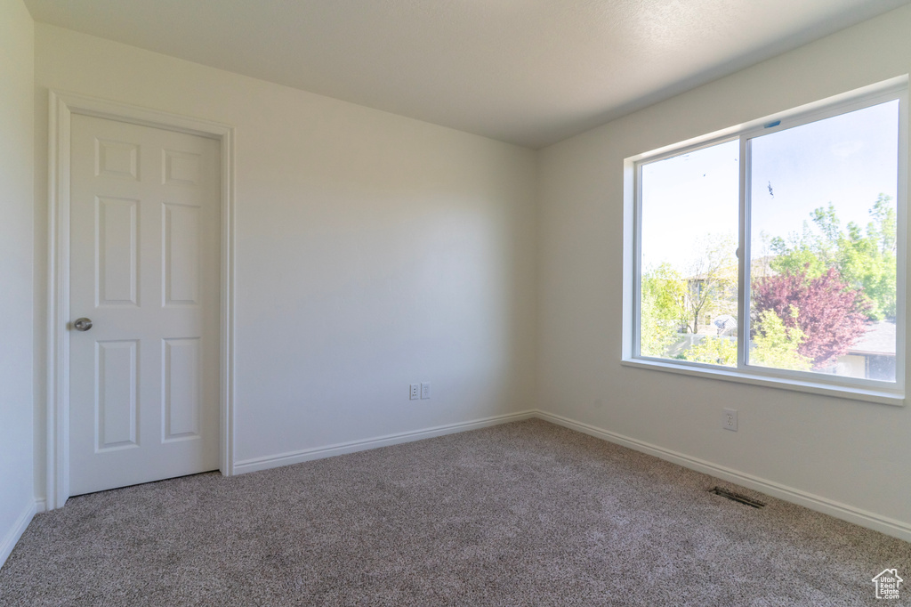Unfurnished room featuring carpet flooring, healthy amount of natural light, and baseboards