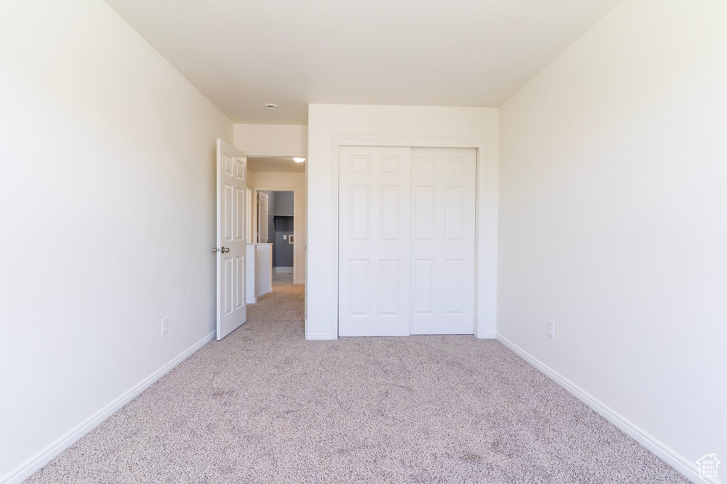 Unfurnished bedroom featuring carpet flooring, baseboards, and a closet