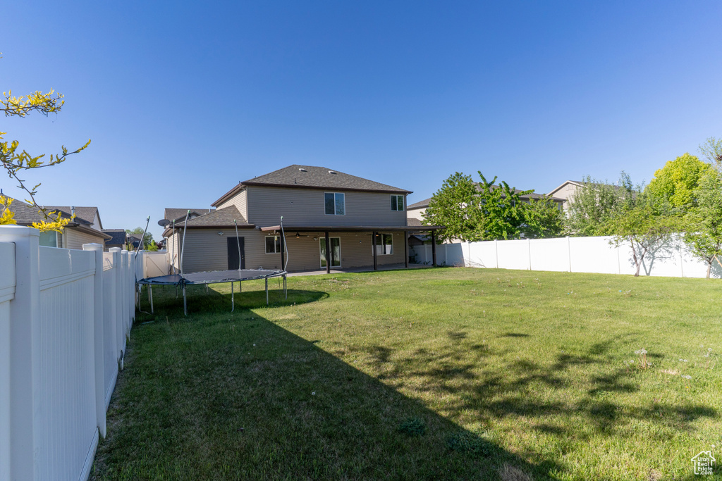 Back of house with a trampoline and a shingled roof