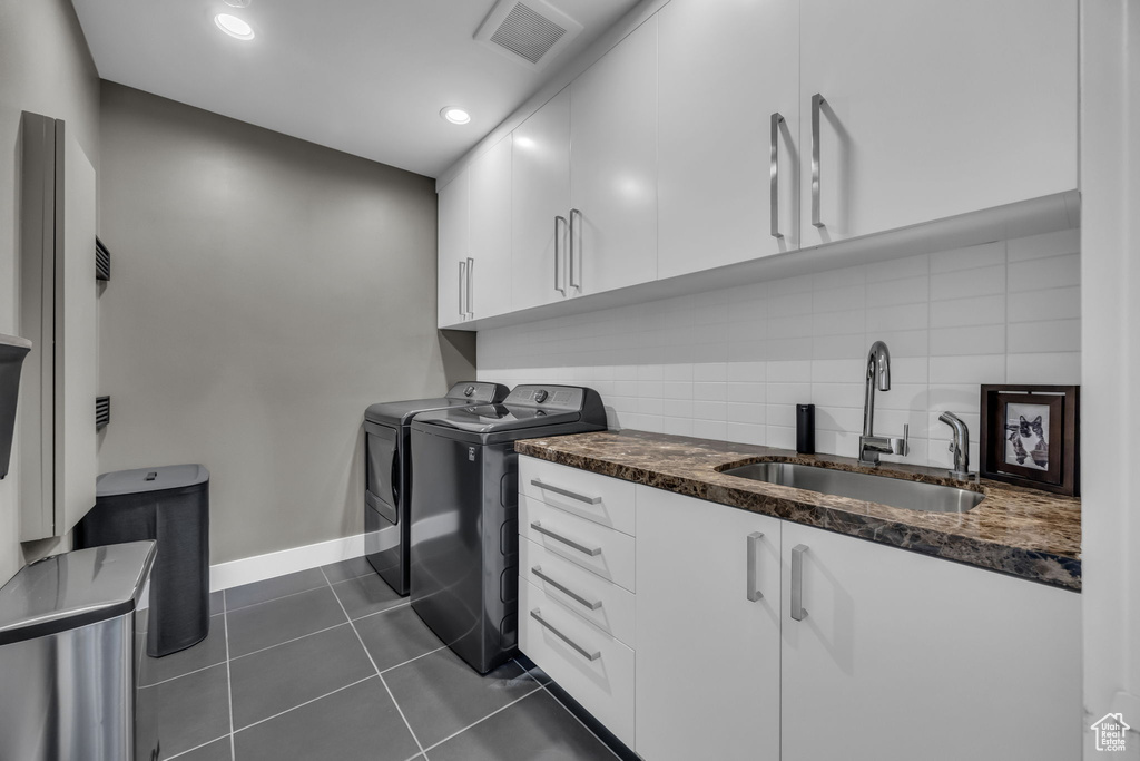 Clothes washing area with separate washer and dryer, cabinet space, baseboards, dark tile patterned floors, and recessed lighting