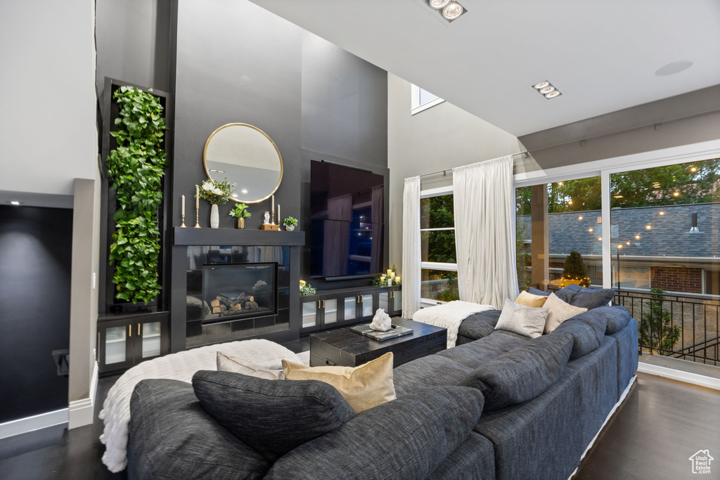 Living room featuring a towering ceiling, a glass covered fireplace, and baseboards