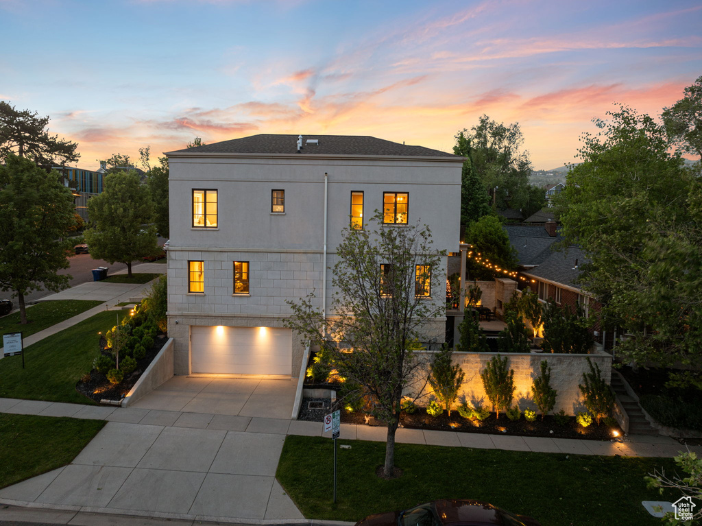 View of front of property featuring a garage, driveway, stairway, a front lawn, and stucco siding