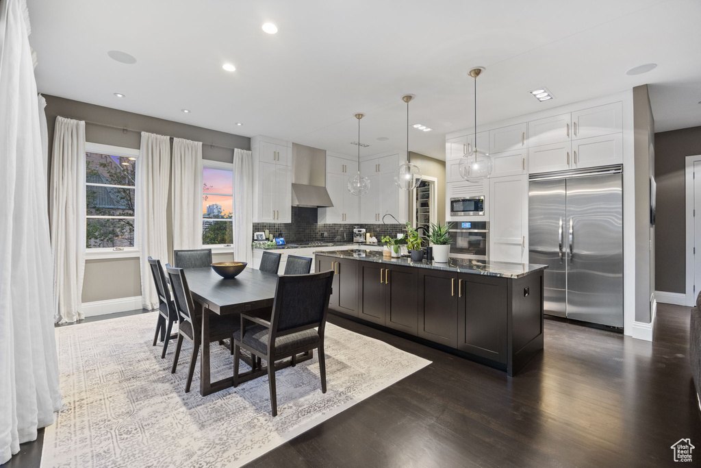 Kitchen featuring built in appliances, baseboards, white cabinetry, backsplash, and recessed lighting