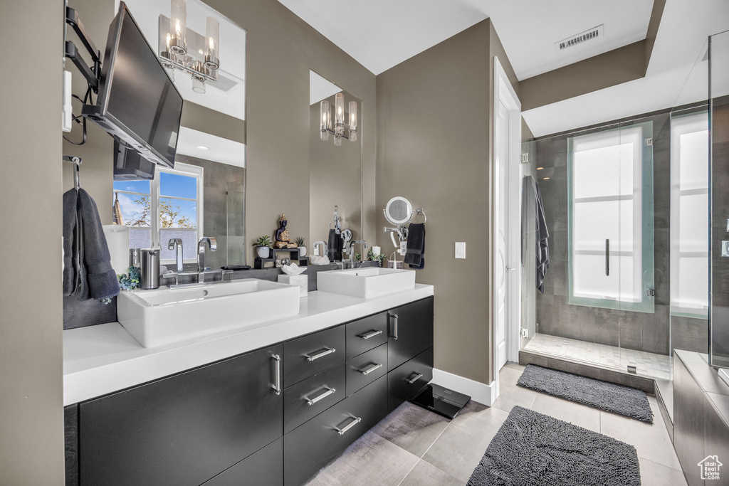 Bathroom featuring a chandelier, a shower stall, double vanity, baseboards, and tile patterned floors