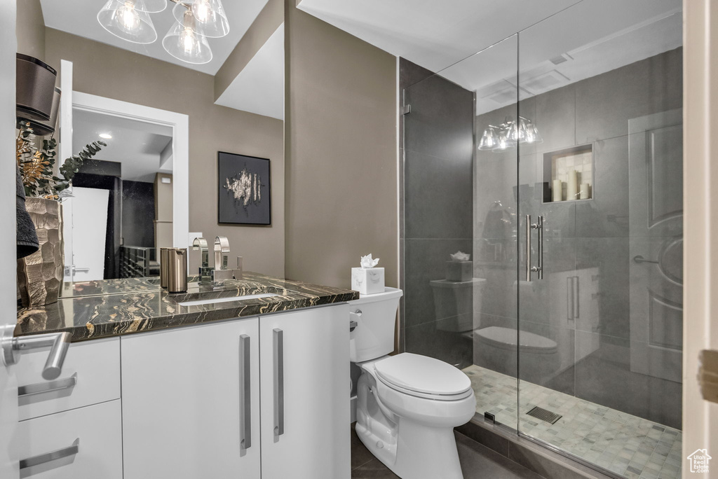 Bathroom with toilet, a shower stall, vanity, and tile patterned floors