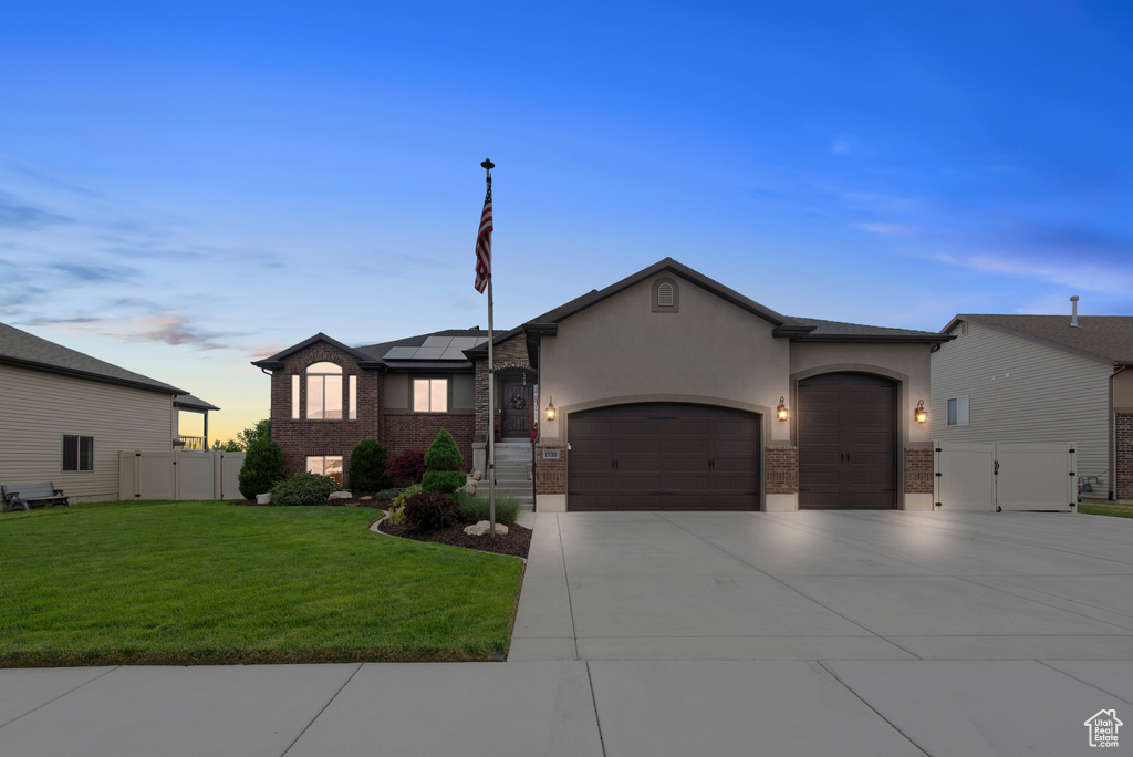 View of front facade with a gate, a garage, stucco siding, driveway, and solar panels