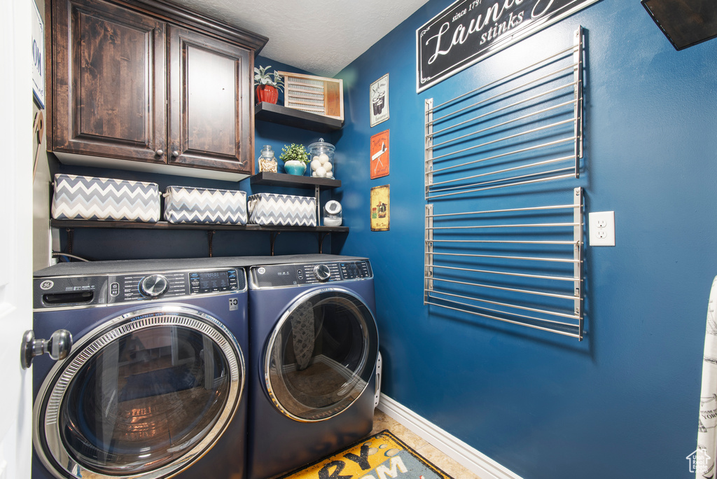 Washroom featuring separate washer and dryer, cabinet space, and baseboards