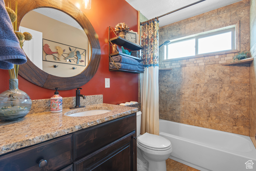 Full bathroom featuring vanity, toilet, and shower / bathtub combination with curtain