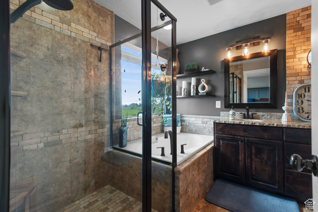 Full bath with a stall shower, a garden tub, and vanity