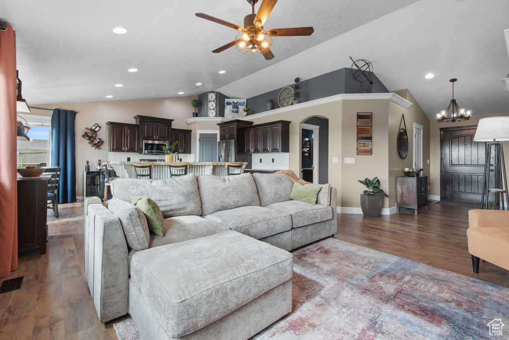 Living room featuring lofted ceiling, a ceiling fan, wood finished floors, baseboards, and arched walkways